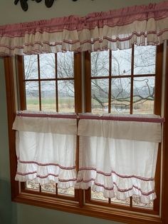 two windows with white curtains and pink trim