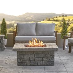 a fire pit sitting on top of a patio next to a couch and table with pillows