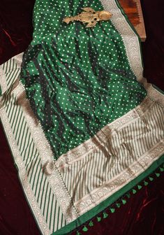 The Bottle Green Banarasi Katan Silk Saree with Chunri Butti, adorned with a skirt border and floral motifs on the pallu, is a magnificent blend of traditional charm and contemporary elegance. Crafted with meticulous attention to detail, this saree exudes sophistication and grace. Whether worn for a wedding celebration, festive occasion, or cultural event, this saree is sure to make a statement and leave a lasting impression. Pair it with traditional jewelry for a classic look or opt for contemporary accessories to add a modern twist. SILK MARK CERTIFIED This saree is ready to wear with fall and pico done. Handmade silk tassels adorn the pallu and add more grace to it. An unstitched blouse fabric is included. *Note: There may be minor variations in the shade, the texture of the product. Hu Green Sharara With Zari Weaving, Traditional Green Pre-draped Saree For Transitional Season, Green Unstitched Zari Weaving Sharara, Green Unstitched Sharara With Zari Weaving, Festive Pre-draped Saree With Border, Green Sharara With Zari Weaving And Traditional Drape, Festive Green Sharara With Zari Weaving, Green Traditional Wear With Zari Weaving For Celebration, Green Sets With Zari Weaving For Transitional Season