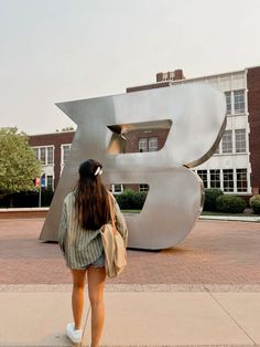 a woman standing in front of a large metal letter b