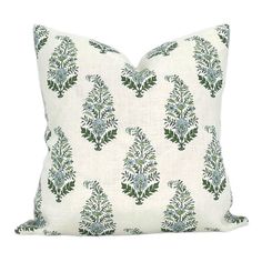 a white pillow with green and blue floral designs on the front, sitting on a white background