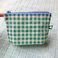 a small green and white checkered bag sitting on top of a carpeted floor