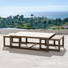 a wooden table sitting on top of a patio next to a large body of water