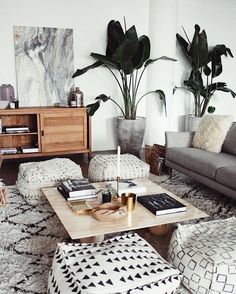 a living room filled with lots of furniture and potted plants on top of them