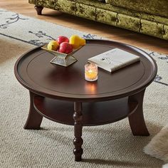 a coffee table with apples, pears and candles on it in front of a couch