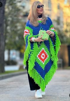 a woman walking down the street wearing a blue and green ponchy