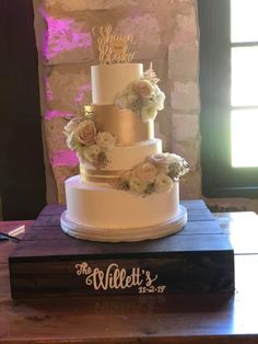 a three tiered wedding cake sitting on top of a wooden table