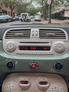 the dashboard of a small car on a city street with cars parked in the background