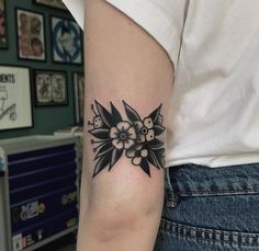 a black and white flower tattoo on the left arm, with small flowers around it