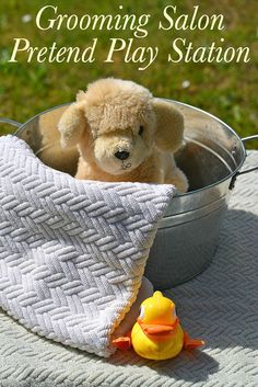 a teddy bear sitting in a pot with a towel and rubber ducky toy on the ground