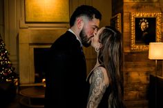 a man and woman kissing in front of a christmas tree