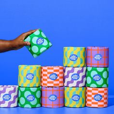 a hand is holding a roll of toilet paper in front of several rolls of toilet paper