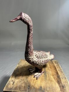 a duck statue sitting on top of a wooden board