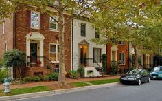 two cars are parked on the street in front of some brick townhouses and trees