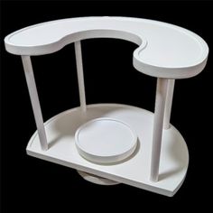 a white table with a circular base and two plates on the top, in front of a black background