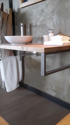 a bathroom sink sitting under a mirror next to a towel rack