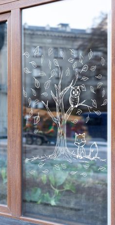 an owl sitting on top of a tree next to a window with leaves drawn on it