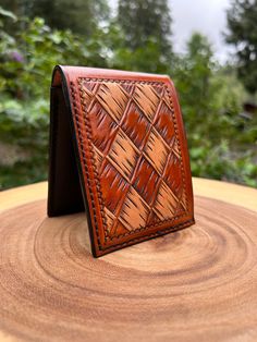 a leather wallet sitting on top of a wooden tree stump in front of some trees