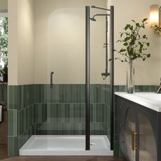 a bathroom with green tiles and a white sink under a large shower stall next to a window