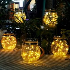 lighted mason jars sitting on top of a table next to plants and potted plants