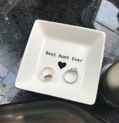 two rings are sitting on a plate with the words best aunt ever written on it