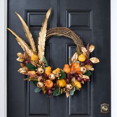 a wreath on the front door decorated with autumn leaves and berries is hanging from it's side