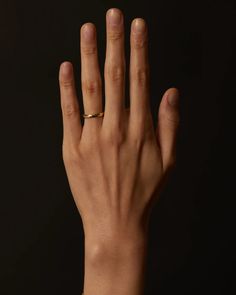 a person's hand with a ring on their left wrist, against a black background