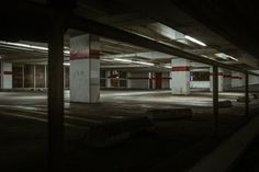 an empty parking garage with red and white striped columns in the center, at night