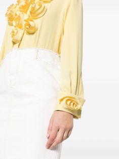 Created with a crepe texture and adorned with delicate floral appliqué, this long sleeve shirt features a classic collar and a concealed front button fastening.blending modern flair with timeless elegance. Mother-of-pearl buttons grace the concealed placket, while crochet and loop closures adorn the cuffs for added luxury. Brighten Up Your Wardrobe Today!Bring the sunshine everywhere you go with our vibrant crepe cotton blouse in bright yellow, adorned with romantic 3D flowers blooming along the front buttoned placket and cuffs of the long sleeves. Designed to elevate your style, this designer flower shirt features a fold-over collar for added flair, ensuring you stand out in every crowd. It's the perfect choice for adding a pop of color and whimsy to your 9-to-5 wardrobe, and even transit Designer Button-up Tops For Spring, Feminine Long Sleeve Shirt For Spring, Designer Long Sleeve Spring Blouse, Designer Spring Workwear Shirt, Designer Long Sleeve Blouse With Ruffles, Designer Spring Tops For Workwear, Chic Long Sleeve Shirt For Spring, Designer Spring Tops With Ruffles, Designer Ruffled Tops For Spring