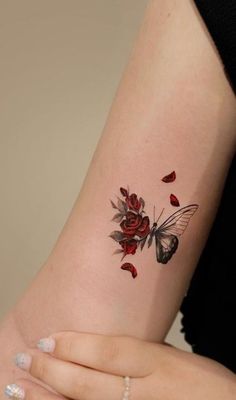 a woman's arm with a butterfly and roses tattoo on it, while the rest of her arm is visible