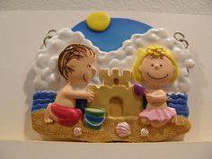 a couple of figurines sitting on top of a sandy beach next to a sand castle