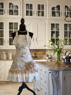 a dress on a mannequin in a kitchen with white cabinets and marble counter tops