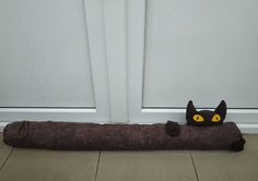 a black cat stuffed animal laying on top of a wooden log next to a door