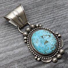 Indulge in the stunning beauty of the Birdseye Kingman Pendant by Tom Lewis. Handcrafted with exquisite attention to detail, this piece features a single Sterling silver setting encasing vibrant turquoise, surrounded by intricate twist and beaded wire. With its impressive size and weight, and a versatile 8mm bale, this pendant is a must-have for any jewelry collection. Make a bold statement and add it to your wardrobe today. Turquoise Jewelry With Intricate Design, Traditional Turquoise Cabochon Jewelry, Unique Engraved Turquoise Jewelry, Oxidized Turquoise Oval Jewelry, Traditional Silver Turquoise Necklace With Gemstone, Collectible Teardrop Turquoise Jewelry, Vintage Turquoise Jewelry With Intricate Design, Turquoise Teardrop Jewelry With Oxidized Finish, Turquoise Jewelry With Oxidized Finish In Teardrop Shape