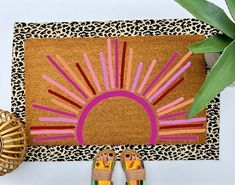 a woman's feet are standing in front of a door mat with the sun painted on it