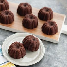 chocolate bundt cakes on a white plate next to a wooden tray