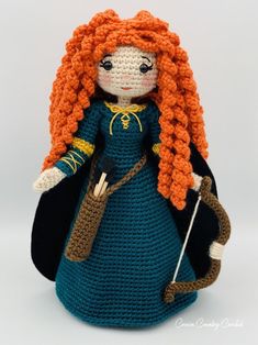 a crocheted doll with long red hair and blue dress is holding a cane