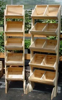 several wooden shelves are stacked on top of each other in front of some potted plants