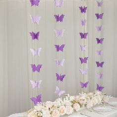 the table is covered with white and purple paper butterflies hanging from it's ceiling