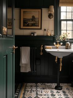 a bathroom with black and white tile flooring next to a green door that leads to a window