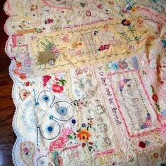 an old quilt is laying on the floor in front of a wooden tablecloth with flowers and hearts