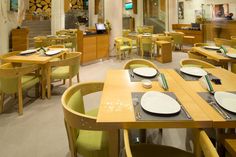 an empty restaurant with yellow chairs and green tablecloths on the dining room tables