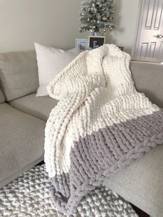 a couch with a blanket on it and a christmas tree in the corner behind it