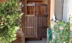 an old wooden door is open in front of a house with potted plants on the porch