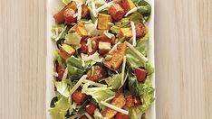 a salad with tofu and lettuce in a white dish on a wooden table