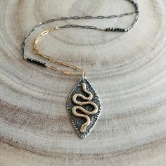 "* Mixed Metal Snake Amulet Necklace * Recycled Metals * Handforged Brass Snake on Sterling * recycled metals * Fused silver dust for rustic texture * Oxidized sterling and 14k gold fill chain * Handmade S-hook clasp and eye  * Pyrite accents  Sizing: * Amulet measures 1.5\" x 0.75\" * Dainty paperclip chain 26\" * The S-Hook clasp can hook into paperclip chain at desired points for adjustable lengths Our Medusa Snake Amulet necklace series feature heavy jewelers brass hand formed snakes soldered to sturdy 925 Sterling silver. We add texture with a hammer and by fusing silver dust to surface. The amulet is then oxidized and polished to highlight the contrast. The asymmetrical mixed metal paperclip chain features pyrite gemstones and an easy to fasten handmade s-hook clasp.  This listing is Hammered Mixed Metal Gold Jewelry, Handmade Unique Jewelry In Mixed Metal, Hammered Gold Mixed Metal Jewelry, Rustic Hammered Gold Jewelry, Rustic Gold Brass Jewelry, Spiritual Gold Necklaces With Oxidized Finish, Rustic Gold Jewelry For Gifts, Spiritual Gold Necklace With Oxidized Finish, Rustic Silver Brass Jewelry