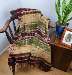 a chair with a blanket on it next to a potted plant