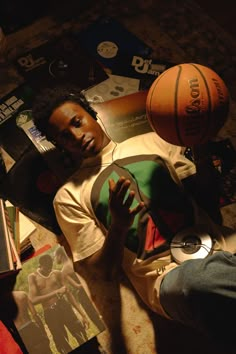 a man laying on the floor next to some basketballs and other sports related items