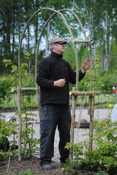 a man standing in front of a garden trellis