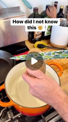 a person holding an object in their hand over a pan with food on the stove